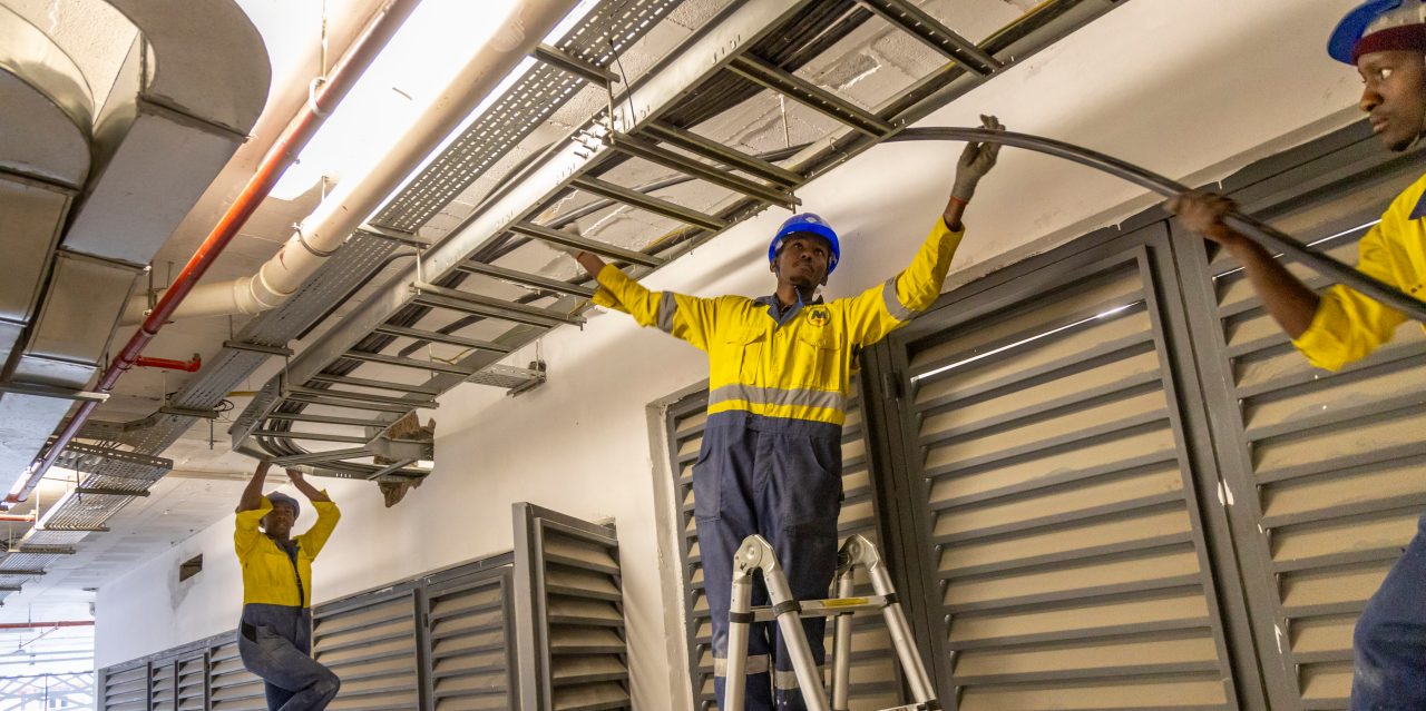 Apprentice Diba Godana Boru, 25, with colleagues laying electrical cables at a new building on General Mathenge drive in downtown Nairobi, whose electricals are contracted to Mehta Electrical, the largest electrical contractor in the region, May 14, 2024.

Diba is an orphan who grew up in a children's home. He was awarded a scholarship to go to a high school, but had to drop out of university opportunity due to lack of school fees. 

PropelA program is a lighthouse project implemented by Swisscontact, funded by Hilti Foundation, and trained at Don Bosco Boys' Town in Nairobi. The first cohort of PropelA apprentices were 100 and were admitted in 2022 (78 male and 22 female apprentices). The application is open to young men and women who are passionate about plumbing and electrical trades. They must have completed secondary school and are aged 18-30.

The program is aimed at economic empowerment, providing rural population and the younger generation in the cities of East African countries with the opportunity to earn their living by giving them training of the skills they need to improve their economic prospects and sustain their livelihoods, to escape poverty and become part of an emerging middle class. 

Photography Georgina Goodwin www.georginagoodwin.com for Hilti Foundation

